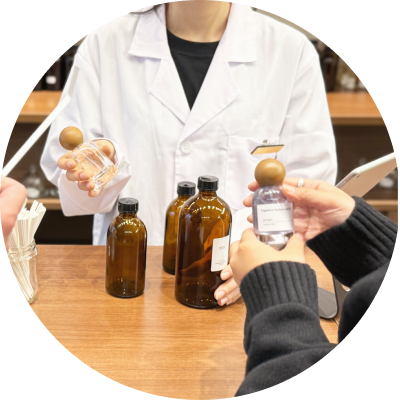 フレグランス体験中、スタッフの案内を受けながら香水ボトルを手に取る来店者。