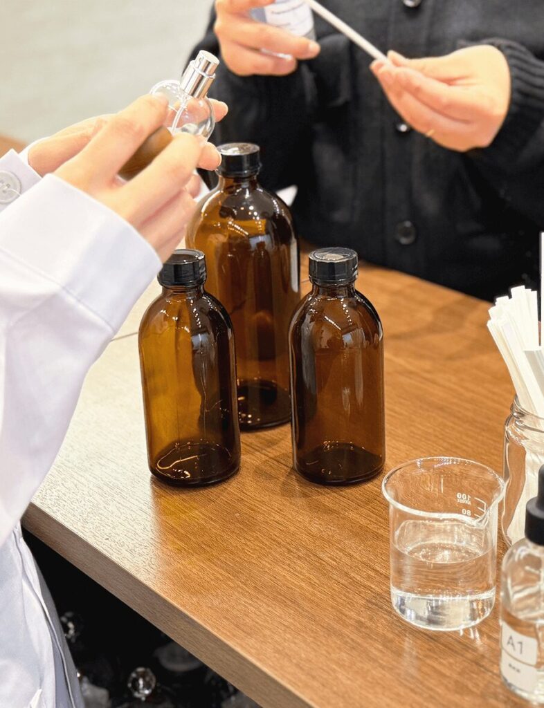 フレグランス工房「香」で香水を調合する様子。香料ボトルを手に取るスタッフの手元。