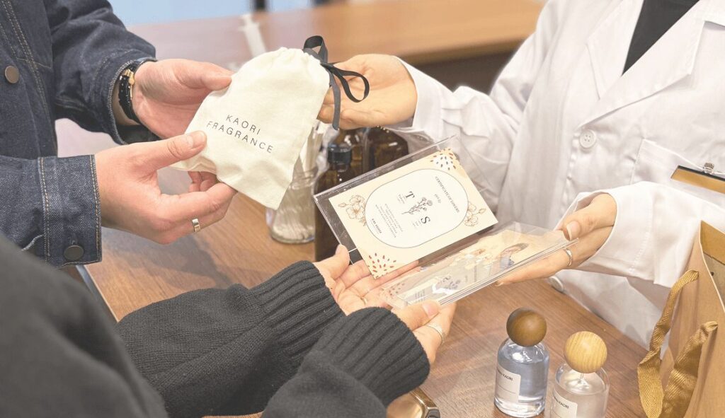 フレグランス工房「香」でギフトを受け取る様子。オリジナル香水を手渡し中。