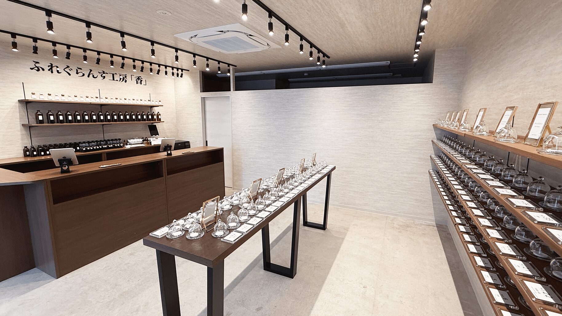 木目のテーブルに並ぶ香料ボトルとビーカー。フレグランス作りの工程を示す。