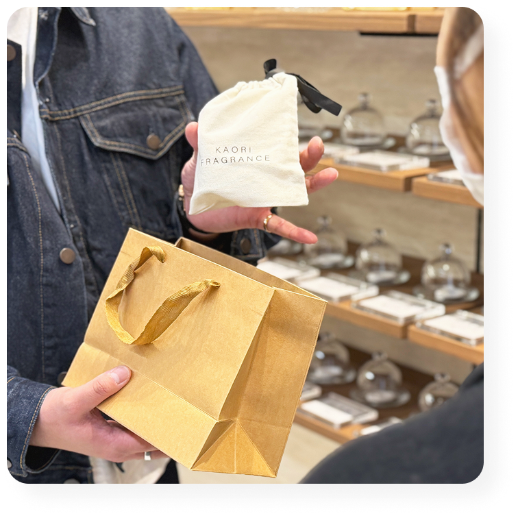フレグランス工房「香」のギフト袋と紙袋を手にするお客様。