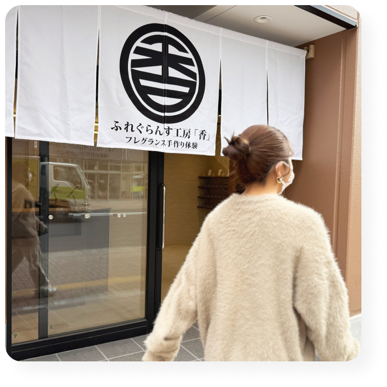 フレグランス工房「香」の暖簾をくぐり、来店する女性の後ろ姿。浅草の香り体験工房。