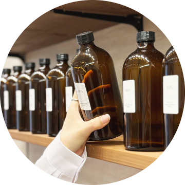 棚に並ぶ香料ボトルを手に取るスタッフの手元。